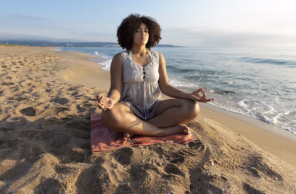 Three people meditate on the beach