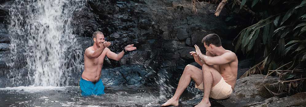 Gay couple playing by a Puerto Rico waterfall