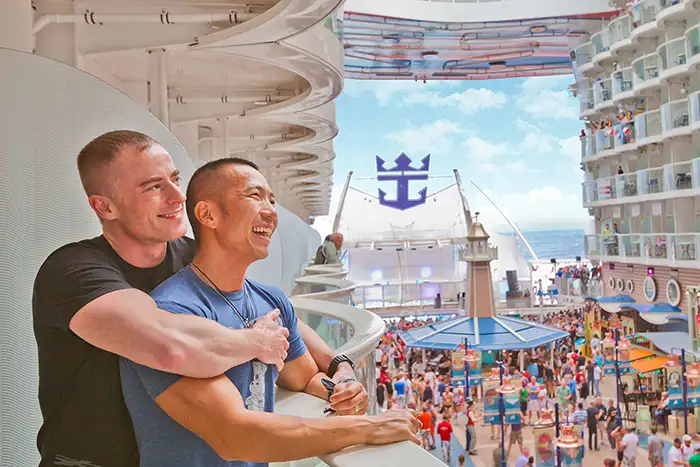 Two men embrace on the inside balcony onboard an Atlantis Cruise