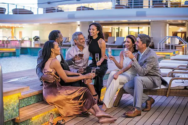 A sophisticated group of adults enjoys a poolside cocktail on a Regent Seven Seas cruise
