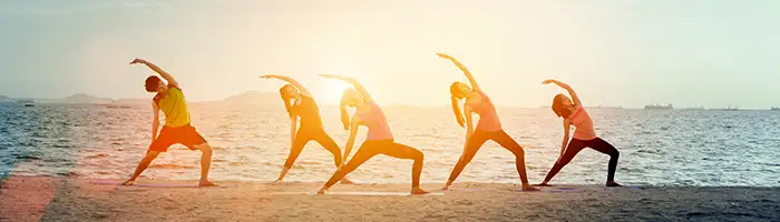 A group of people does yoga on the beach at sunrise