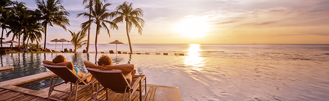 A couple sitting beach side at their villa