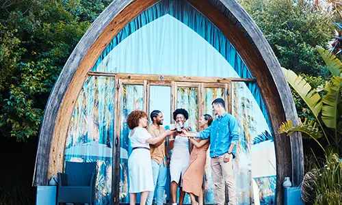 A family with grandparents, parents, and kids sitting in the pool at a luxury villa.