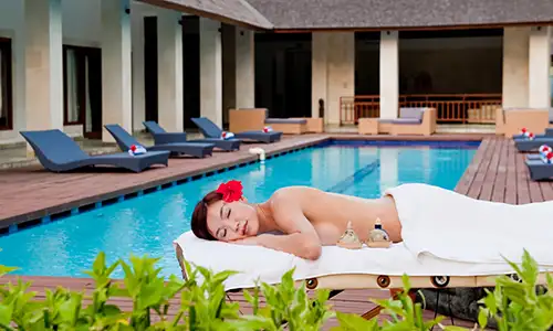 A woman relaxes by the pool of a private luxury villa